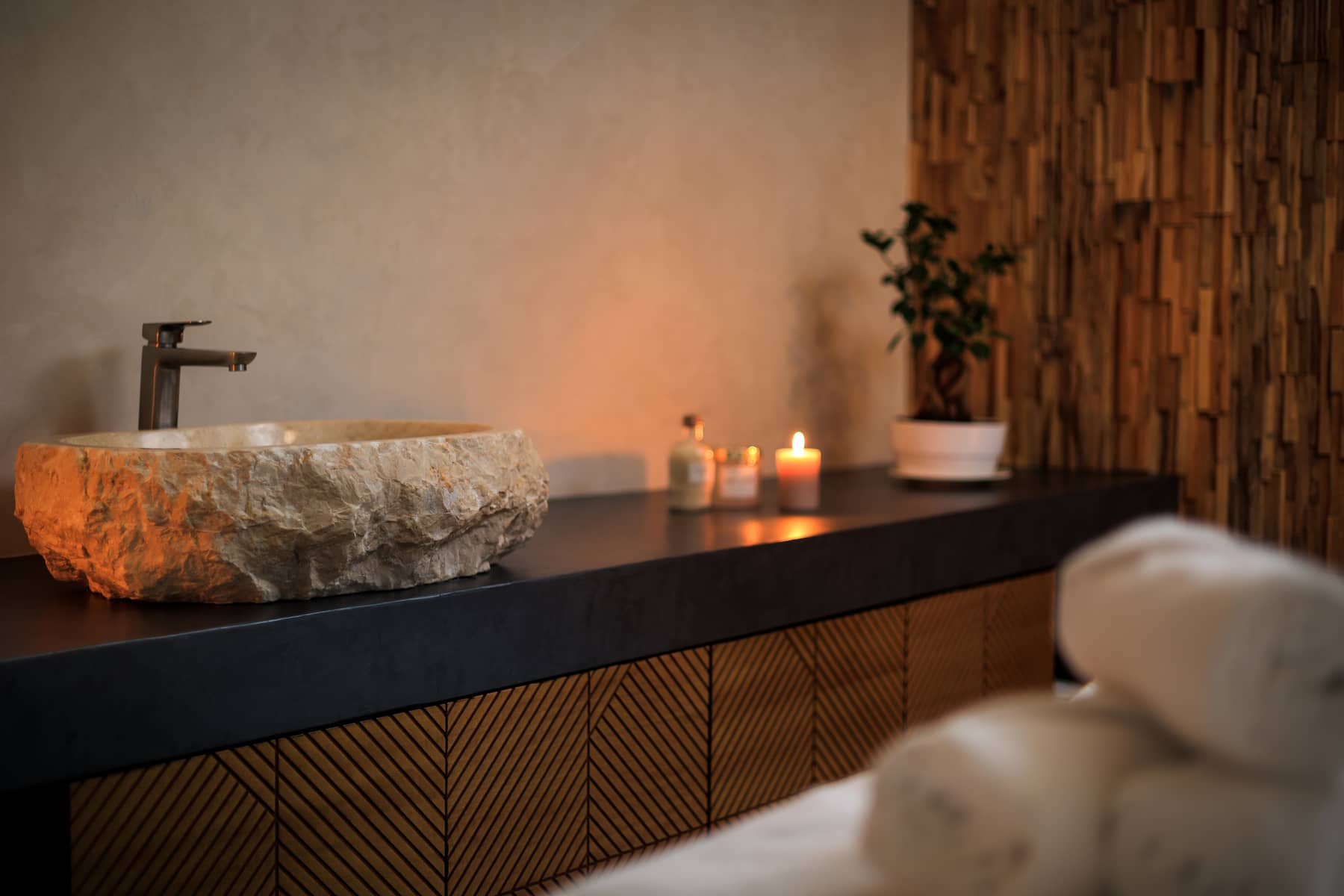 Calm spa treatment room with a massage bed prepared for a guest, warm lighting and folded towels.